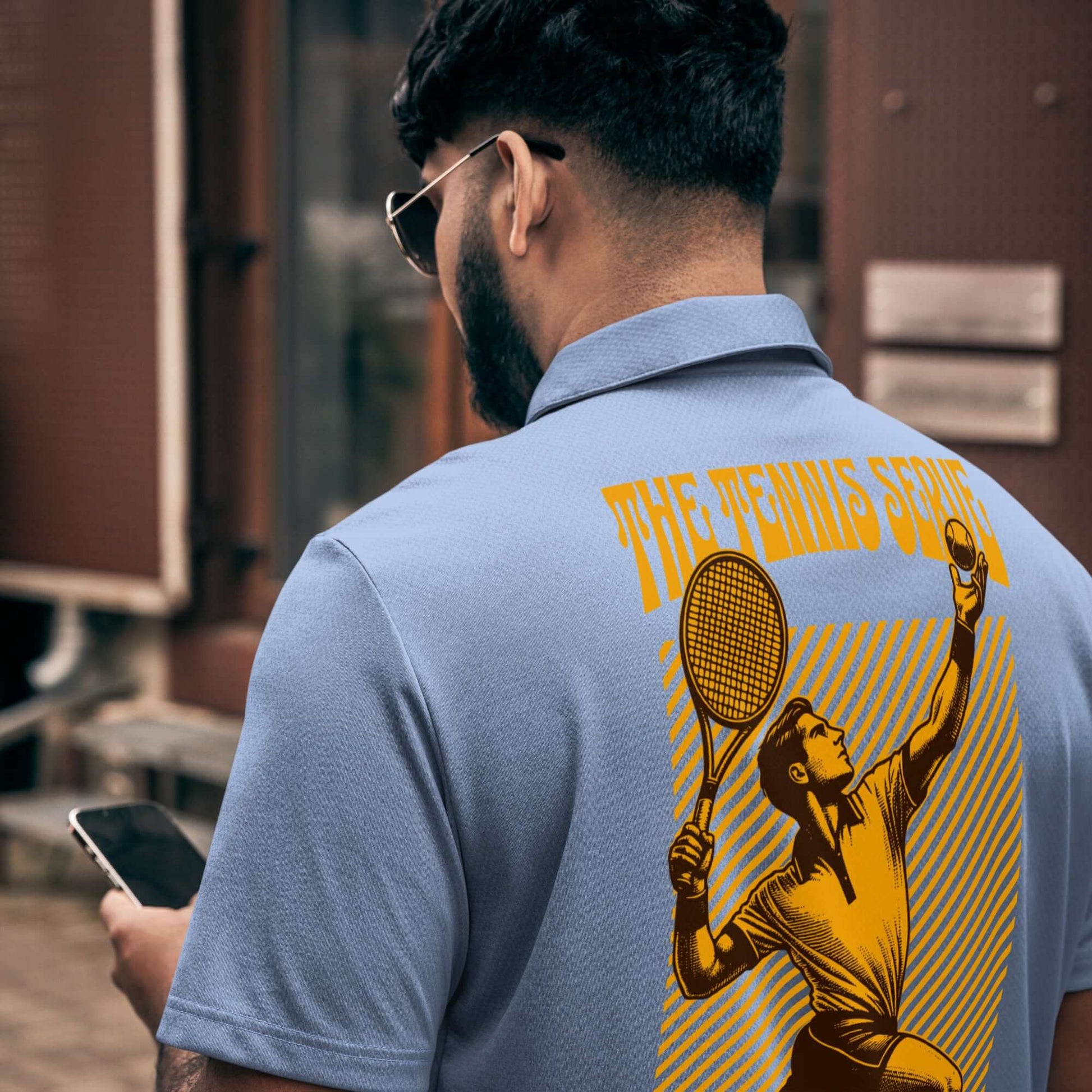 Man wearing Adidas Tennis Serve Polo with golden serve illustration, showcasing athletic and stylish design on back, outdoors.