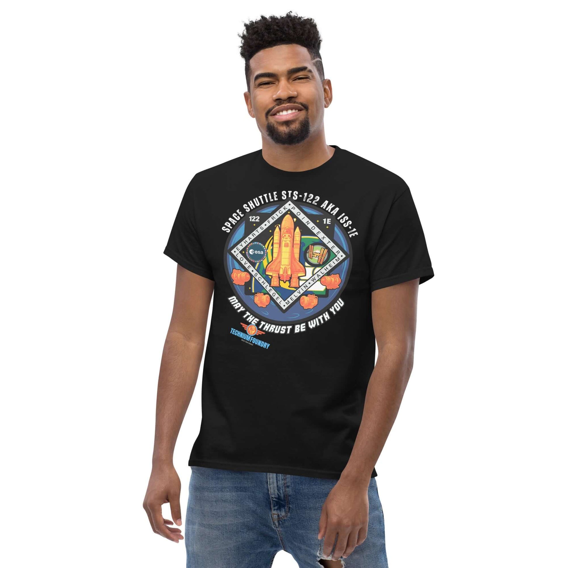 Man wearing black "May The Thrust Be With You" space shuttle tee, featuring the STS-122 mission patch. Part of Science & Tech Apparel Collection by Technium Foundry.