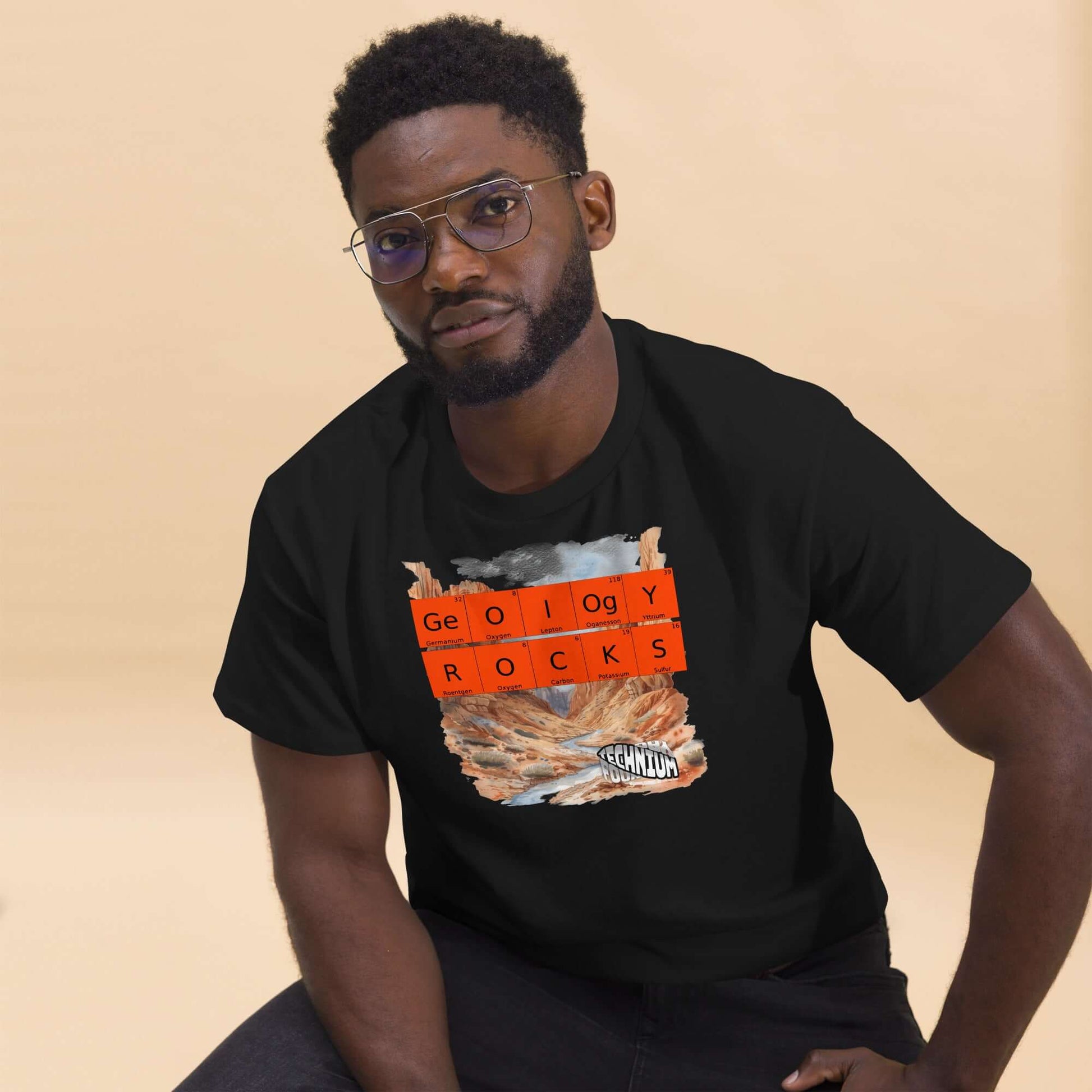 Man wearing black GEOLOGY ROCKS T-shirt by Technium Foundry featuring periodic elements with a geological landscape design.