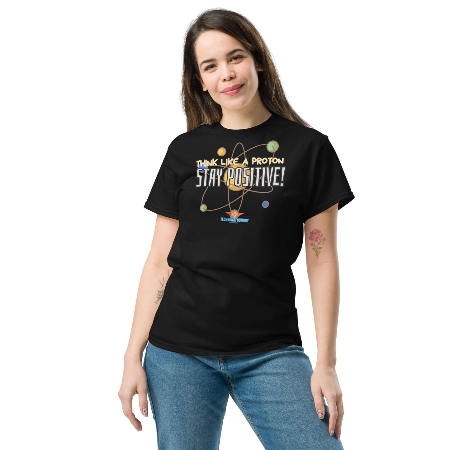 Woman wearing "Think Like a Proton, Stay Positive!" tee, featuring a design combining particle physics and motivational message.