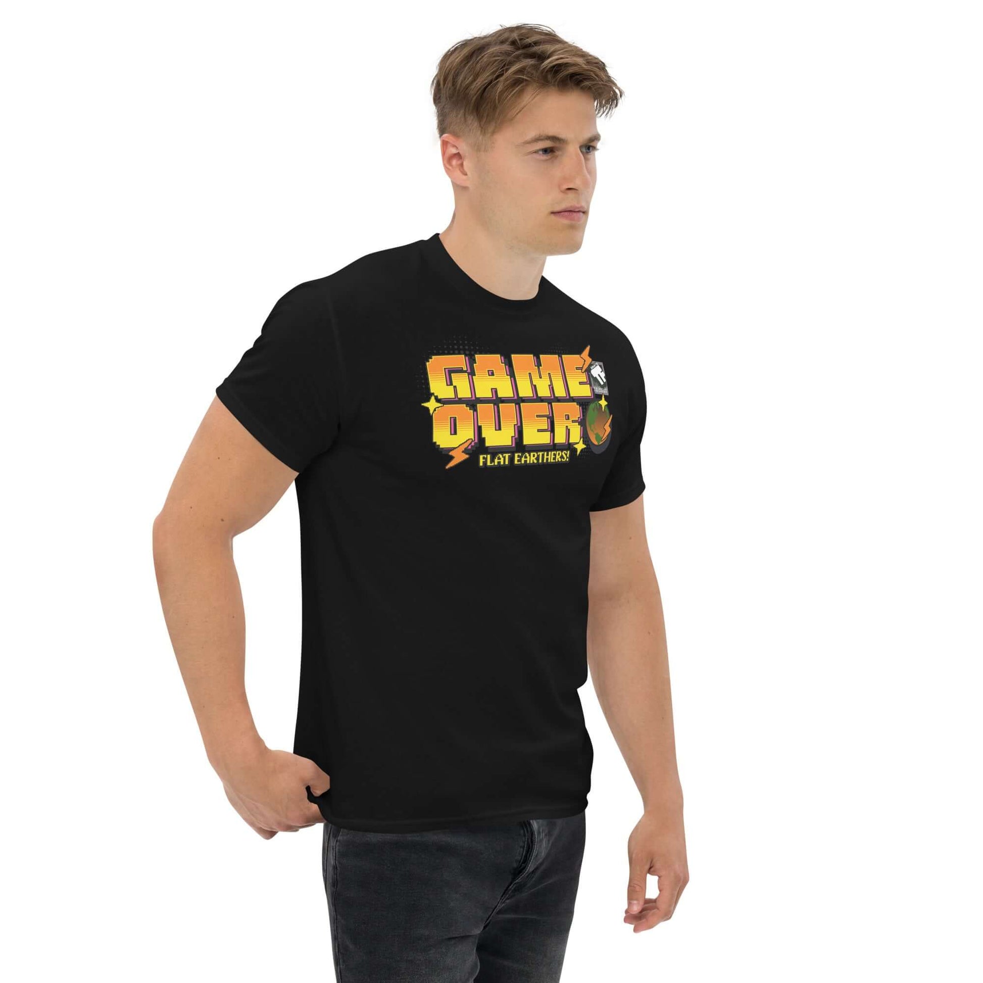 Man wearing black “Game Over, Flat Earthers” T-shirt with a pixelated Earth design, inspired by classic 16-bit arcade style.