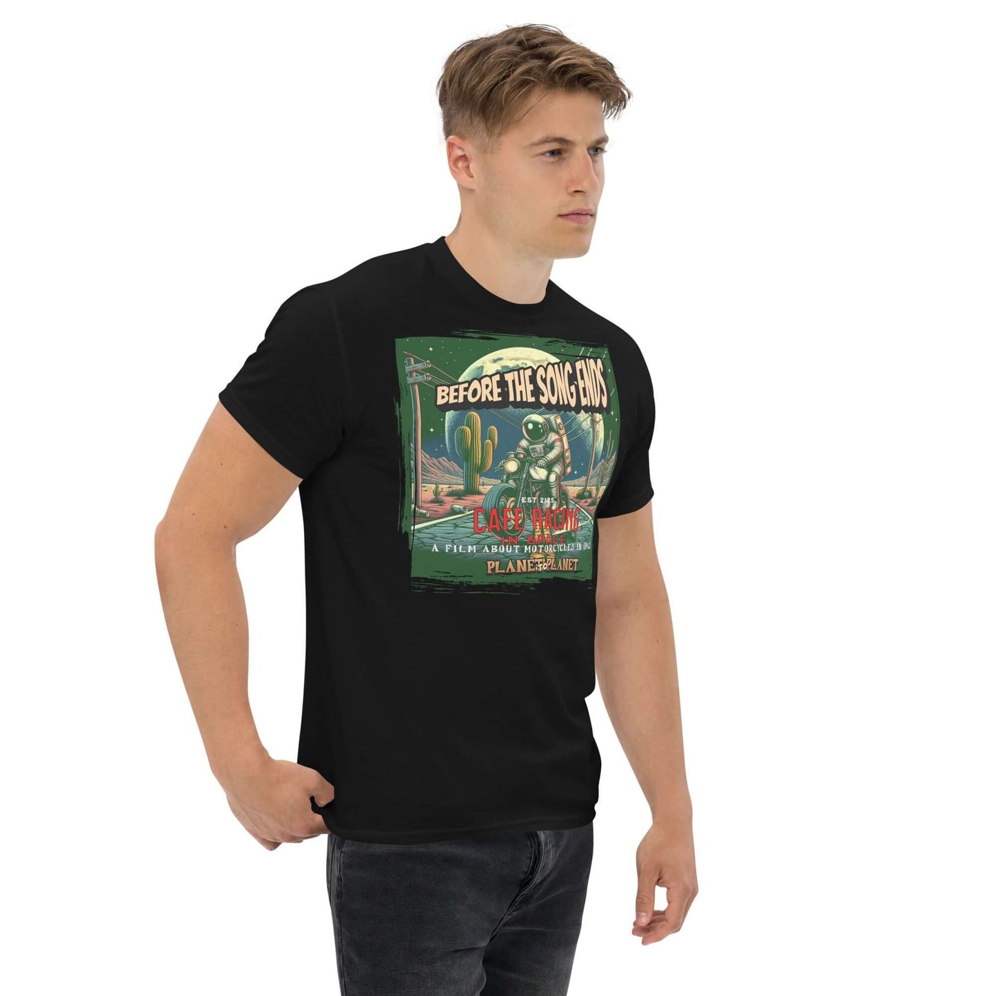 "Man wearing Cafe Racer Space T-Shirt featuring astronaut and desert scene with cacti and celestial bodies, vintage movie poster style"