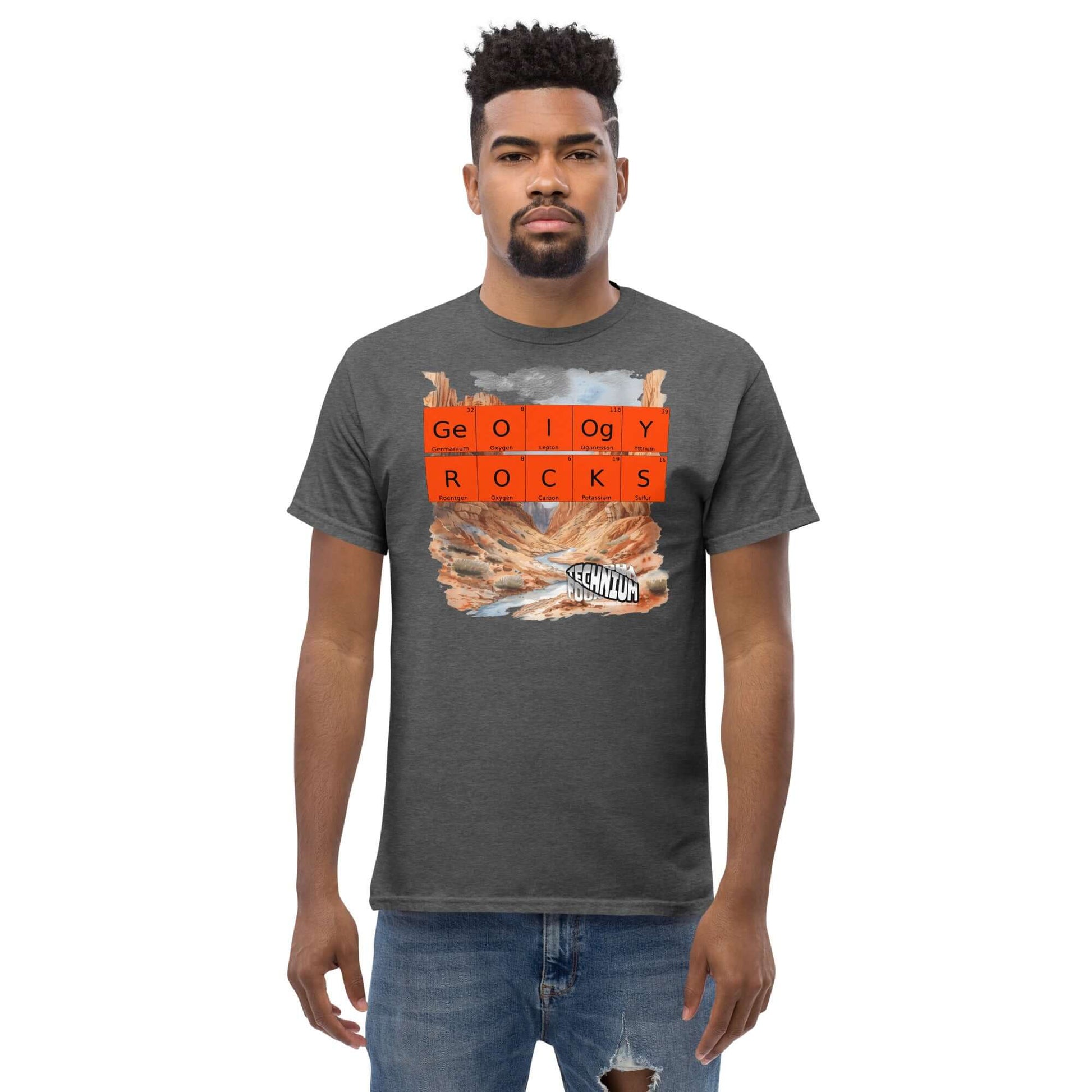 Man wearing "GEOLOGY ROCKS" T-shirt by Technium Foundry with periodic table design and geological landscape background.