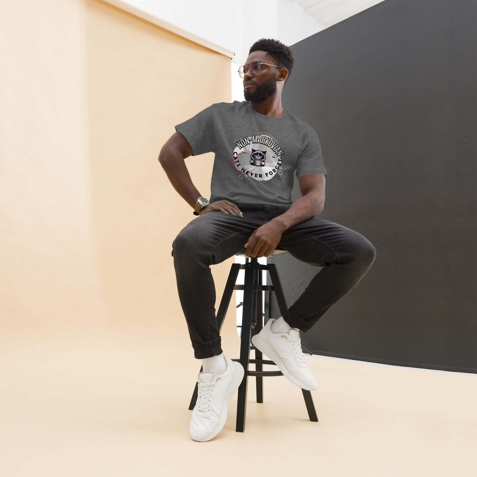 Model wearing Non-Markovian Cat T-Shirt, gray, with grumpy cat design in studio setting, black jeans and white sneakers