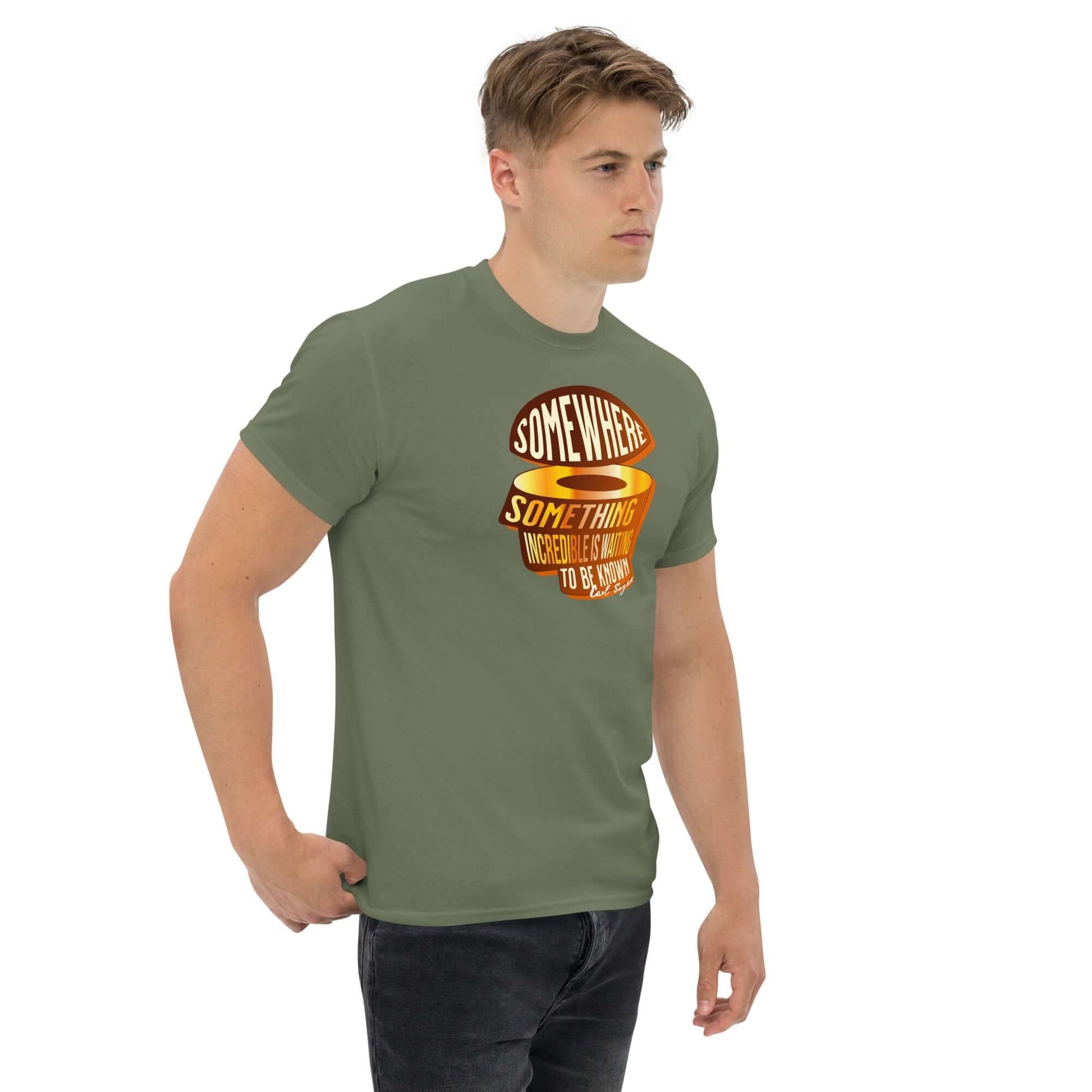 Man wearing 'Somewhere, Something Incredible' Carl Sagan quote t-shirt in sunset colors on olive green fabric, casual style.