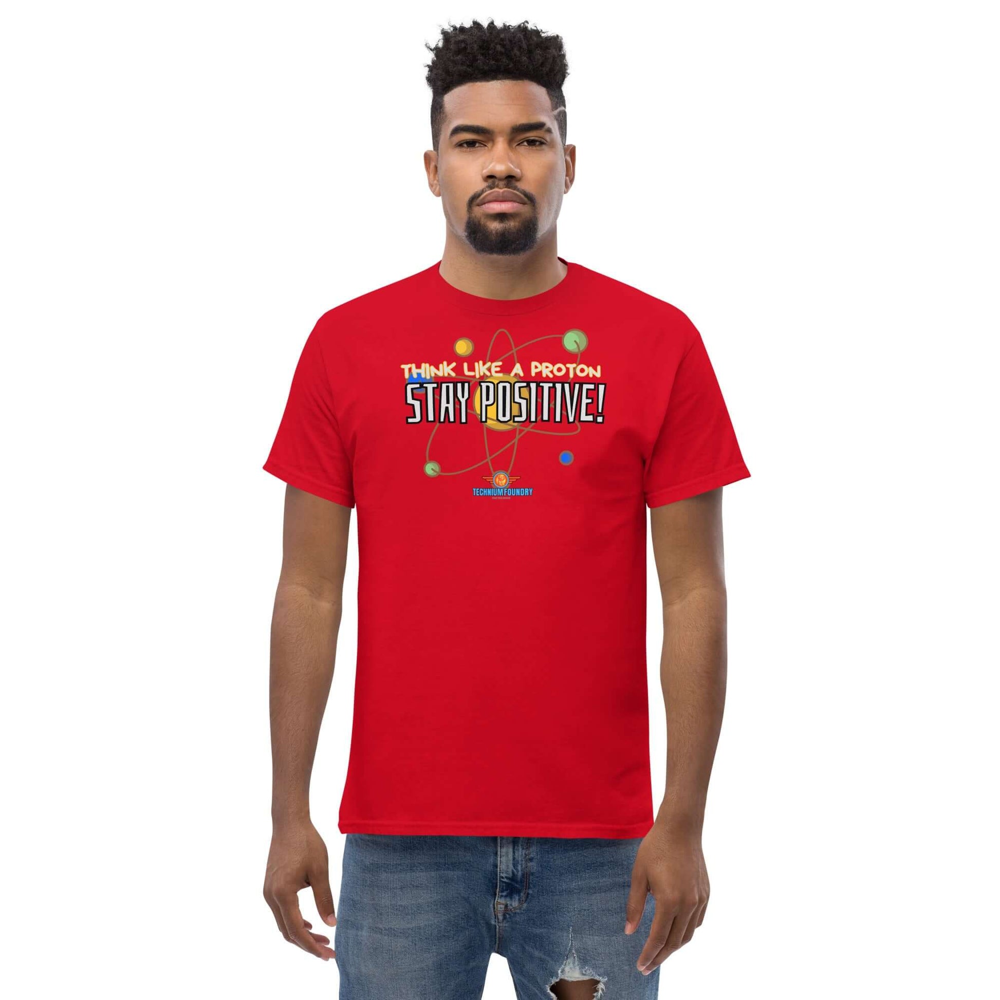 Red "Think Like a Proton, Stay Positive!" tee featuring a motivational physics message worn by a model.