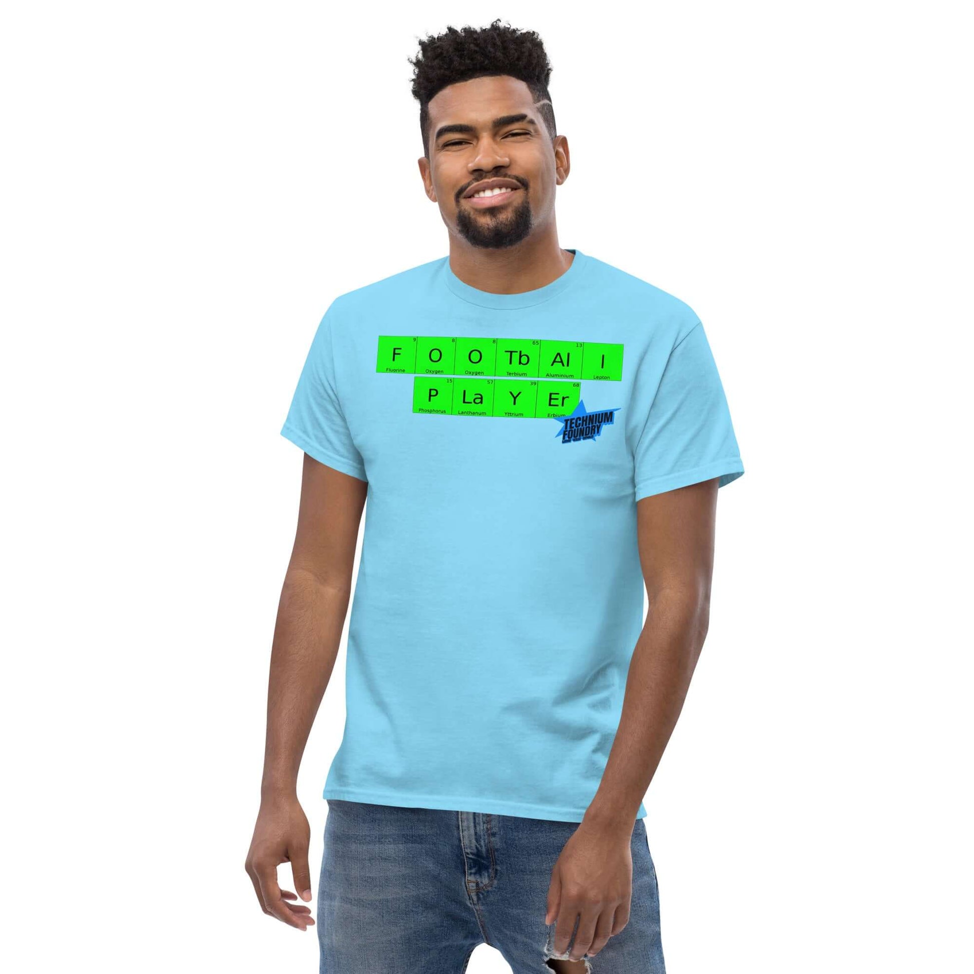 Football Player T-Shirt by Technium Foundry in blue with periodic table design, worn by a smiling person.