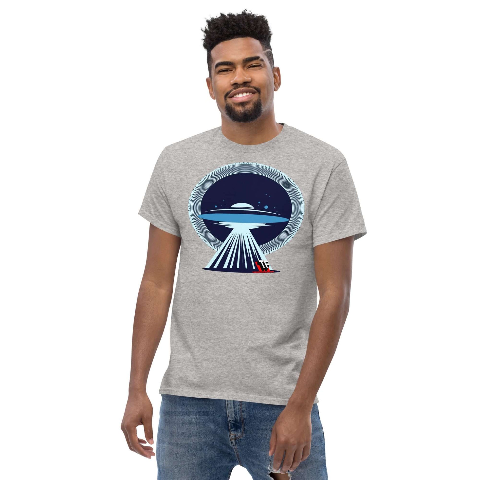 Man wearing a UFO Christmas T-shirt by Technium Foundry, featuring a UFO beaming up Santa's sleigh, blending holiday cheer with alien tech.