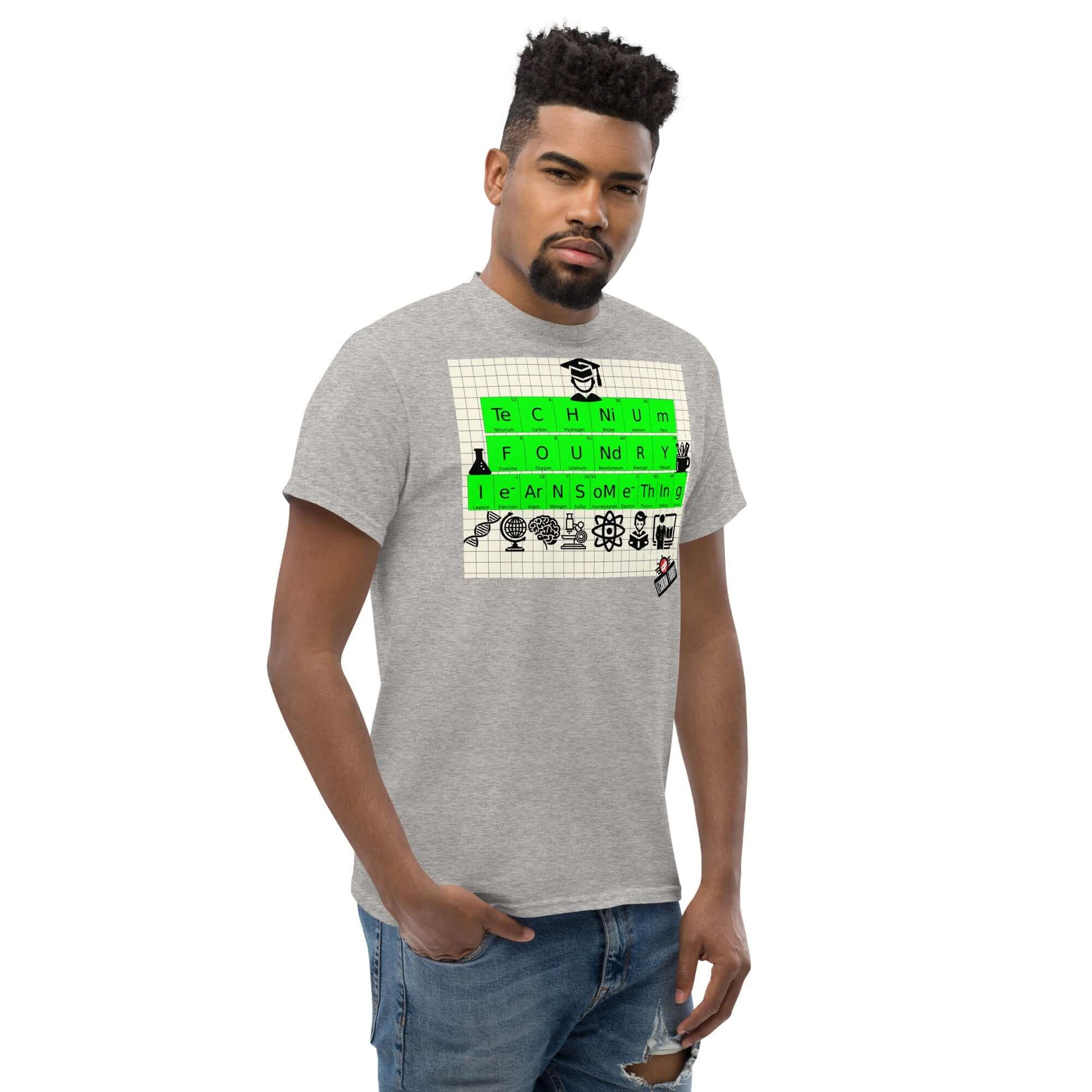 Man wearing Technium Foundry T-shirt with periodic table elements design on graph paper background, featuring educational icons.