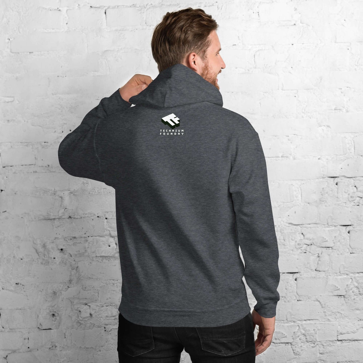 Rear view of a man wearing a dark gray Starfish Prime hoodie against a white brick wall.