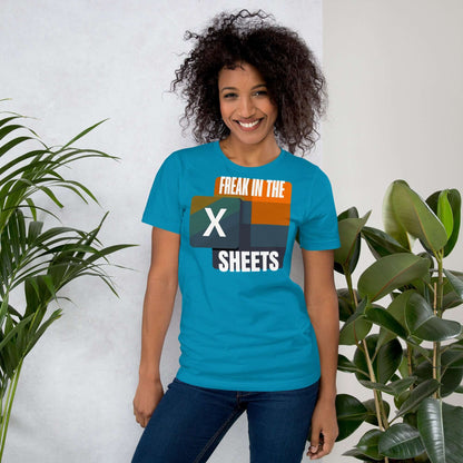 Person wearing a blue 'Freak in the Sheets' T-shirt with retro Excel icon design, surrounded by green plants.