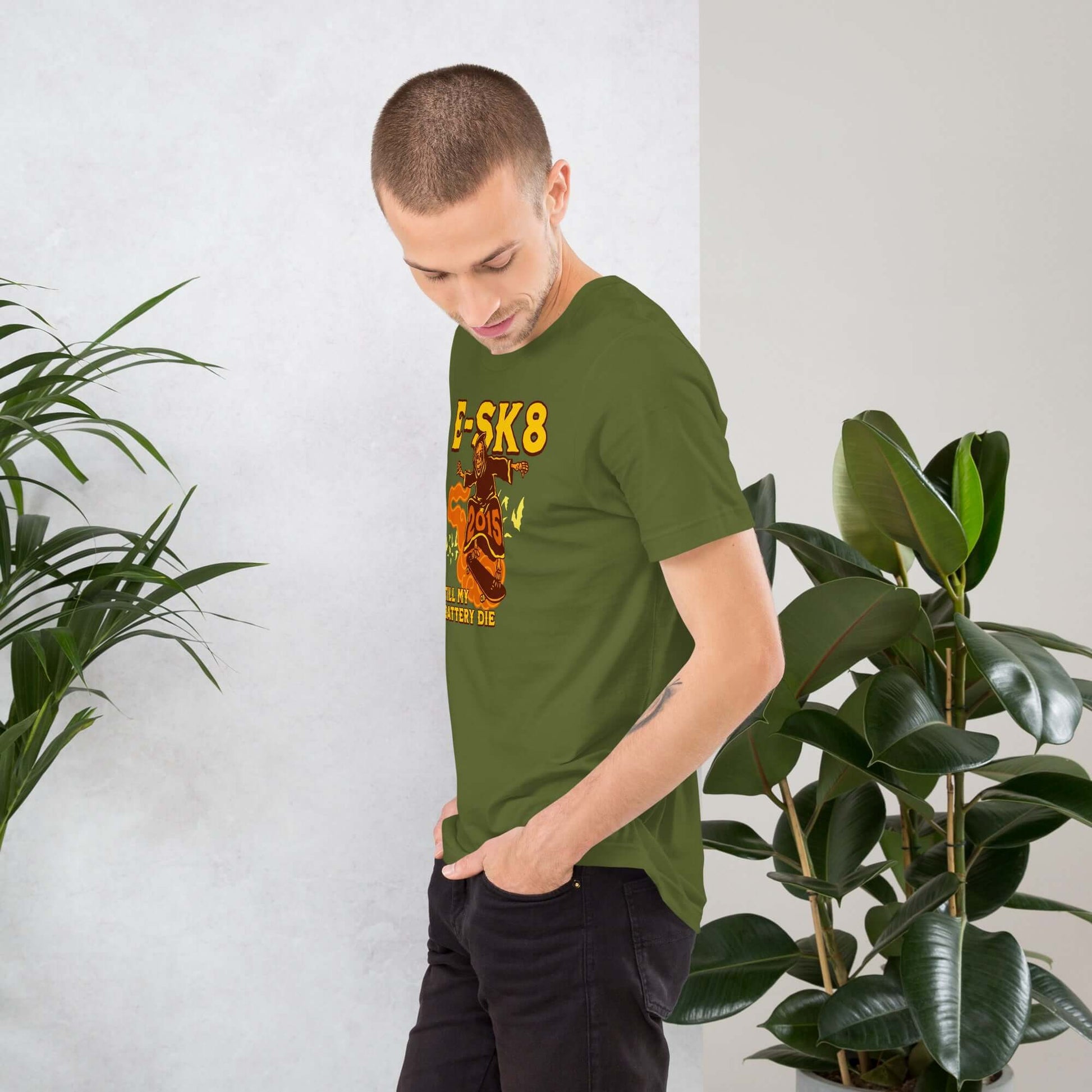 Man wearing E-SK8 Till My Battery Dies T-Shirt featuring Grim Reaper electric design, with plants in the background.