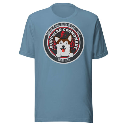 Blue t-shirt featuring Laika the space dog with a retro emblem design and 'Puppular Cosmonaut' text, celebrating cosmic exploration.