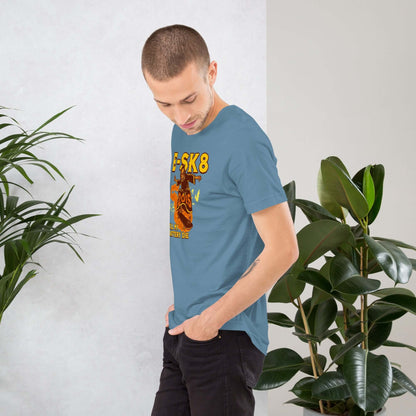 Man wearing blue E-SK8 Till My Battery Dies T-Shirt featuring Grim Reaper design in front of indoor plants.