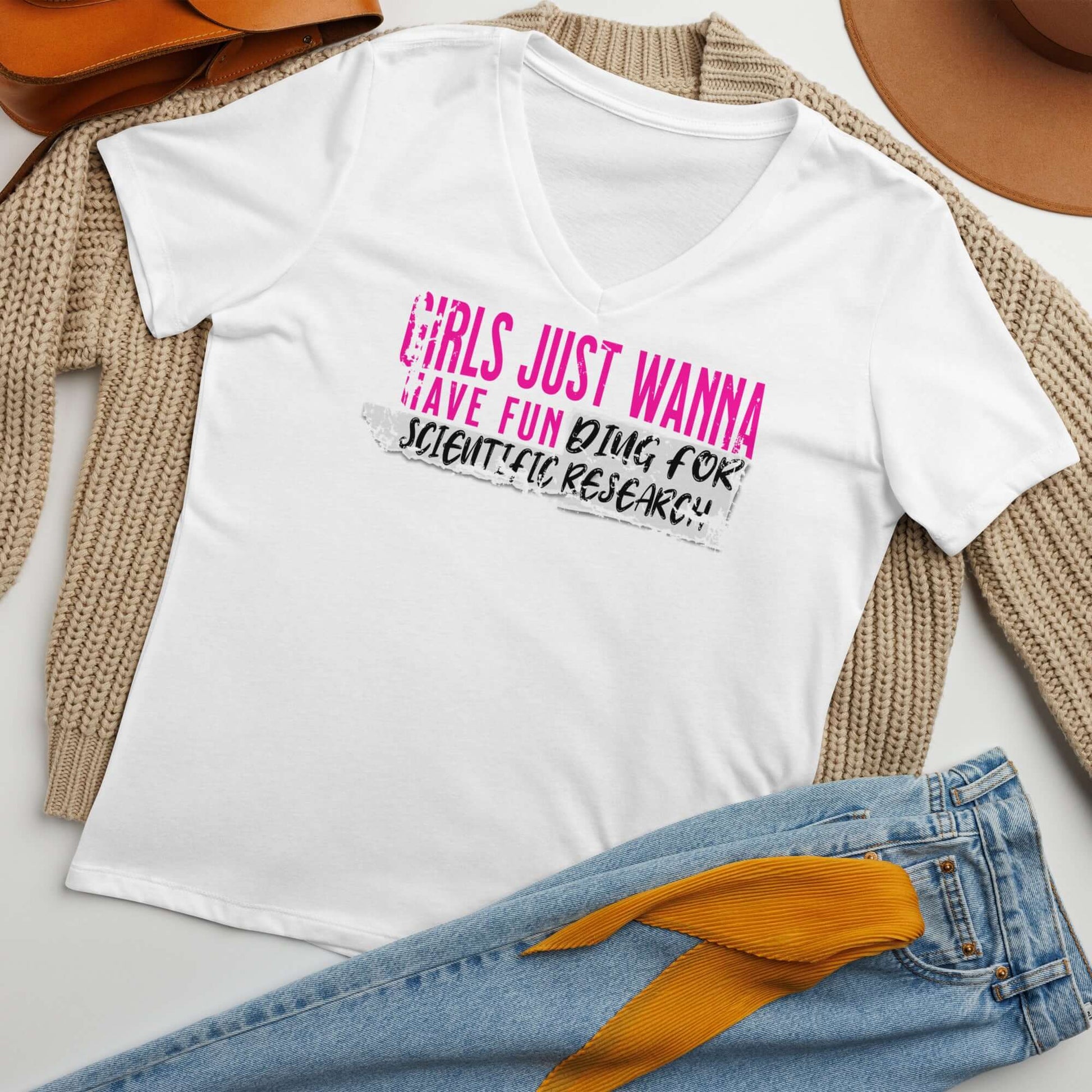 White T-shirt with 'Girls Just Wanna Have Fun Doing Scientific Research' text in pink and black on display with jeans and hat.